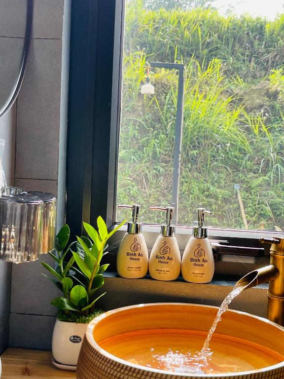 a sink with four bottles of soap in a window at Bình An House in Sapa