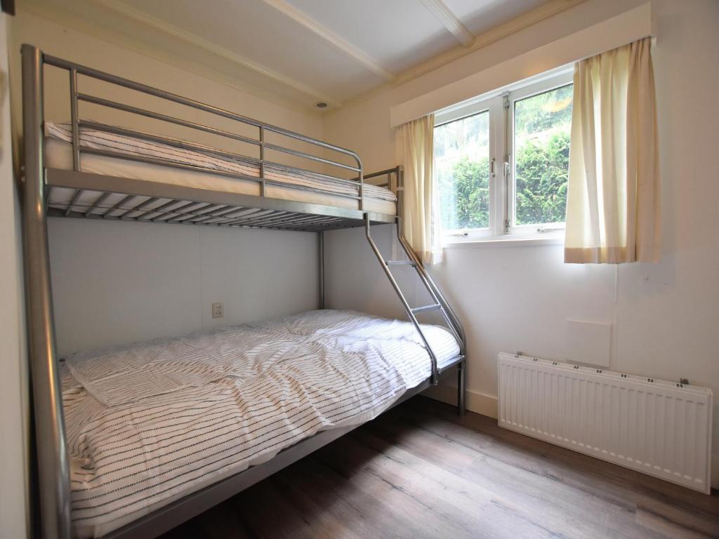 een slaapkamer met een stapelbed en een raam bij Chalet in Veluwe near Sauna Drôme, cleaning included in Putten
