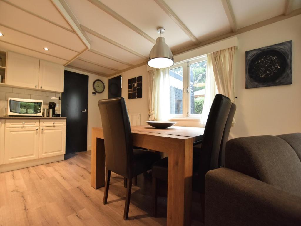 een keuken met een eettafel en stoelen bij Chalet in Veluwe near Sauna Drôme, cleaning included in Putten