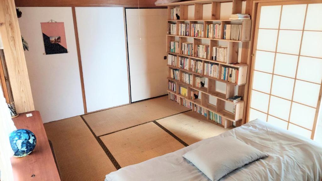a bedroom with a bed and a book shelf with books at 民泊 inori in Dekiji