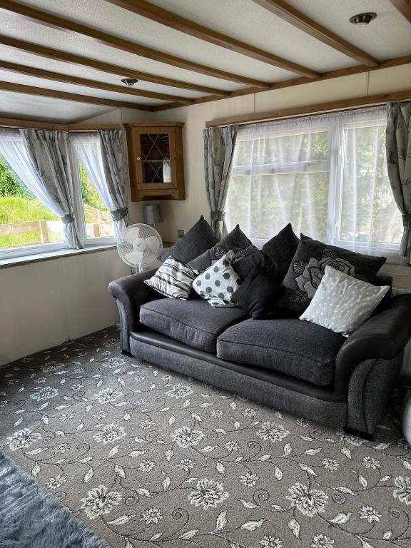 a couch sitting in a living room with windows at 77 Glenfinart Caravan Park in Dunoon