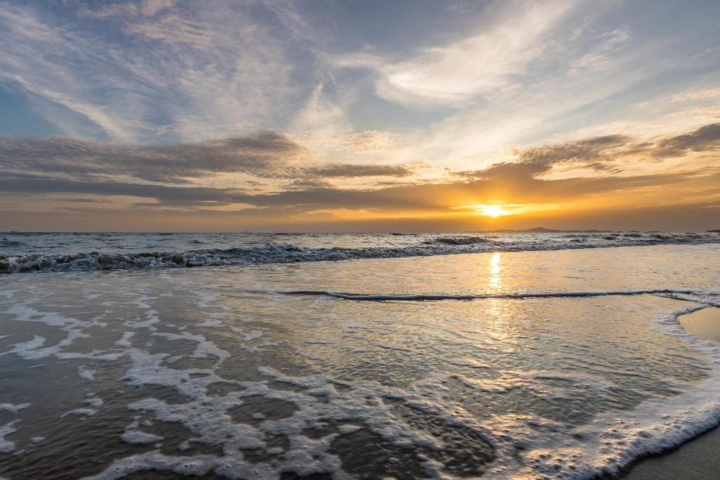 a sunset on a beach with the ocean at LUX- VERANDA PATTAYA - Residence in Jomtien Beach