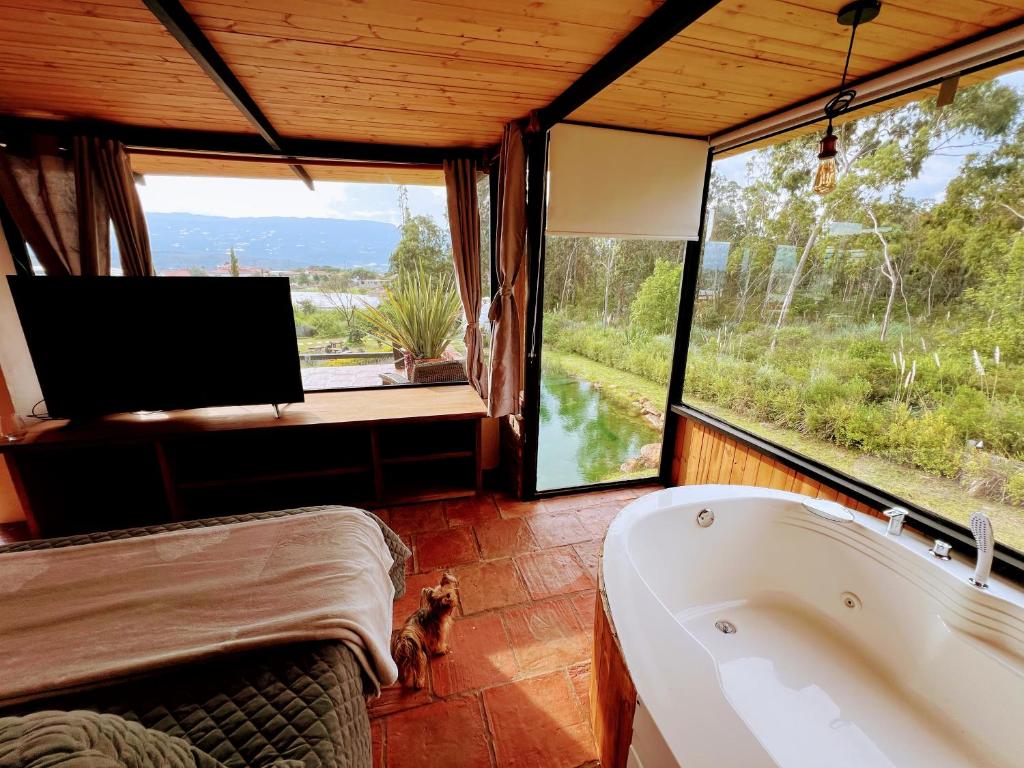 a bath tub in a room with a tv and a view at Glamping Pozo Azul, Villa de Leyva in Villa de Leyva