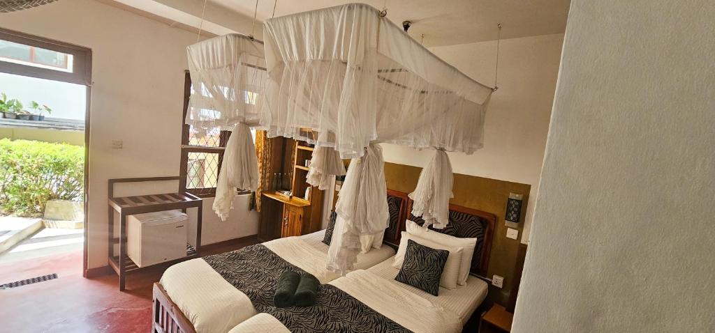 a bedroom with a canopy bed with white curtains at Hilltop Guest House in Ella