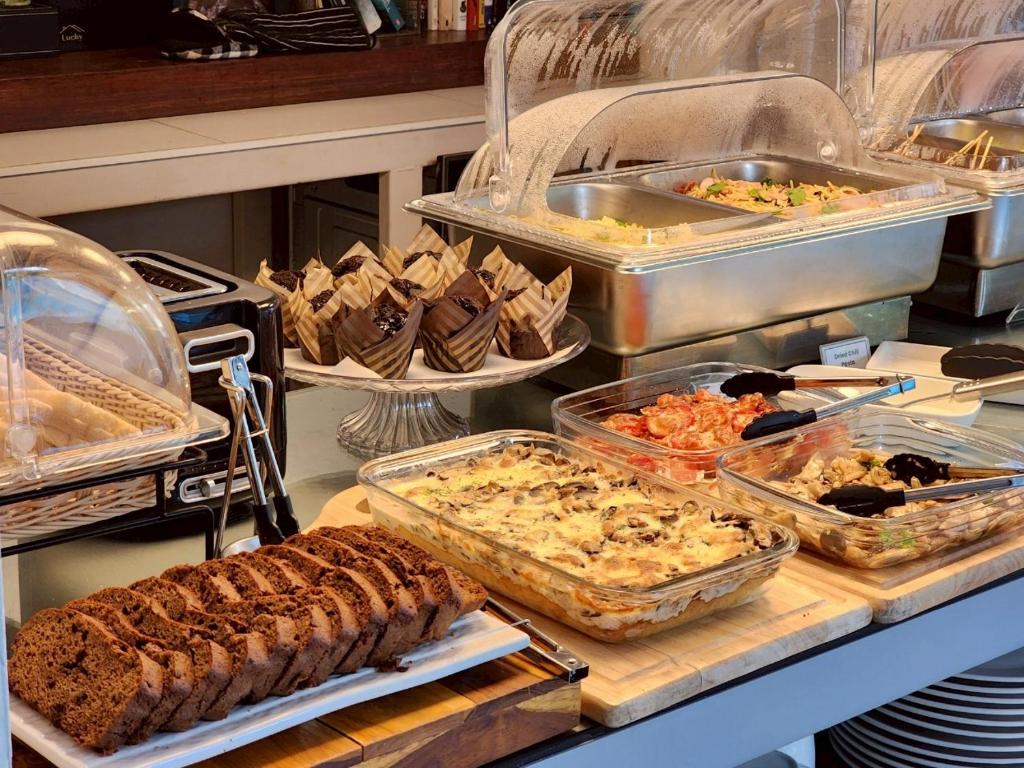 A covered breakfast buffet with breads, hot dishes, salad, and condiments.