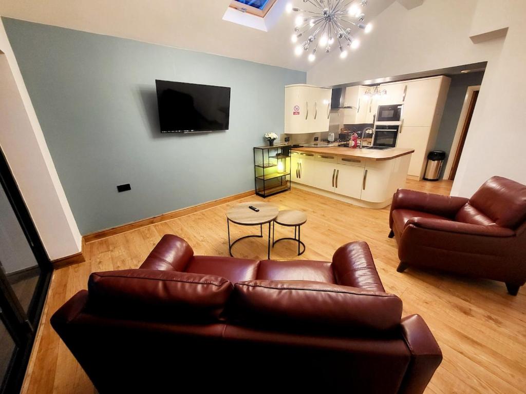 sala de estar con 2 sofás de cuero y cocina en 3-Bed Family Haven with Free Parking, en Huddersfield