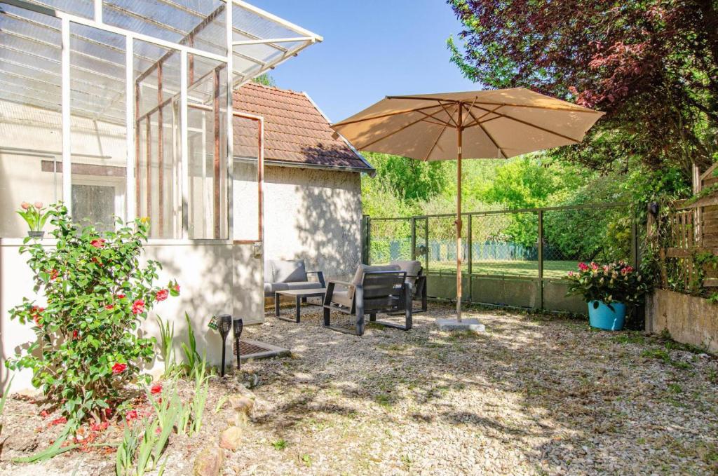 un patio con una mesa y una sombrilla en L'annexe, en Saint-Hilaire-sous-Romilly