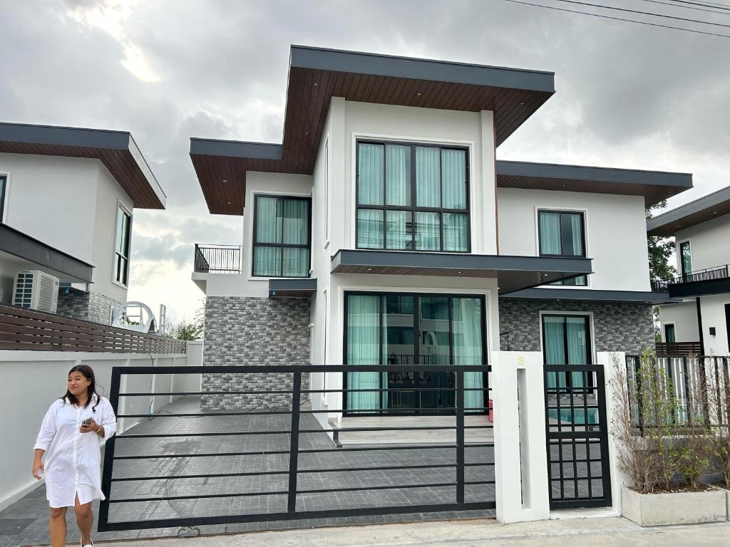 a woman standing in front of a house at Auqa Pool Villa by DRH in Ban Bung