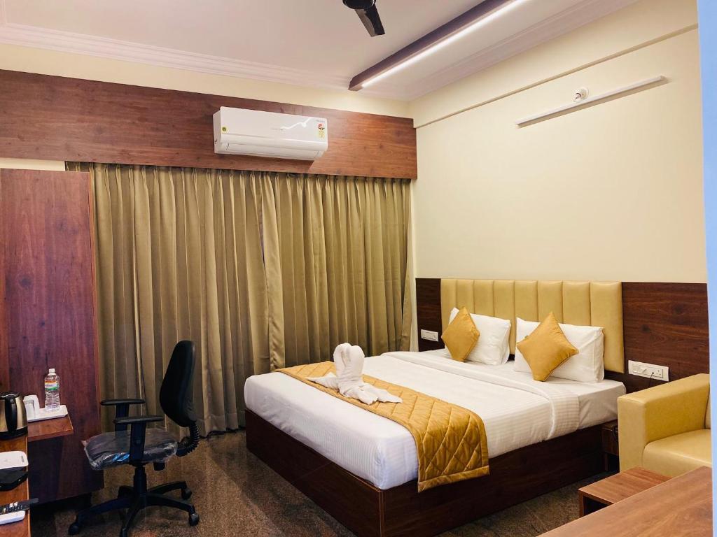 a hotel room with a bed and a desk and a chair at Hotel Sahara Tree in Bangalore