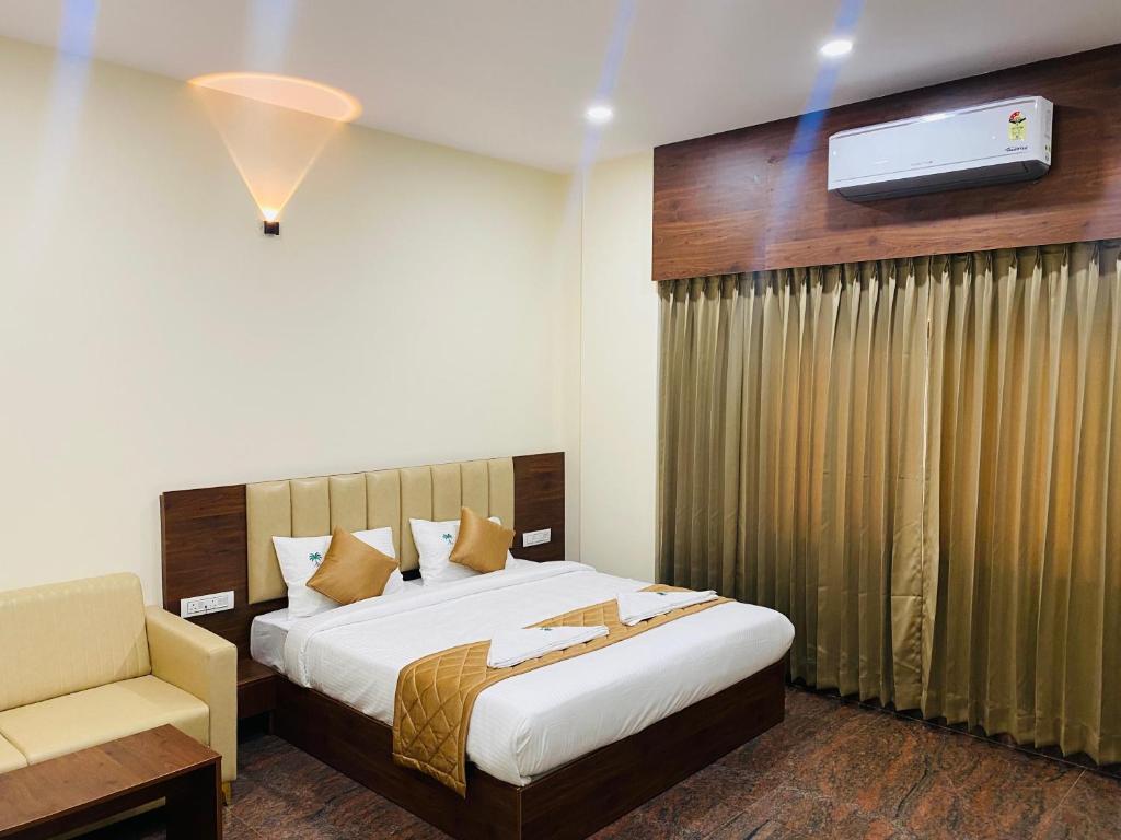 a bedroom with a bed and a couch and a tv at Hotel Sahara Tree in Bengaluru