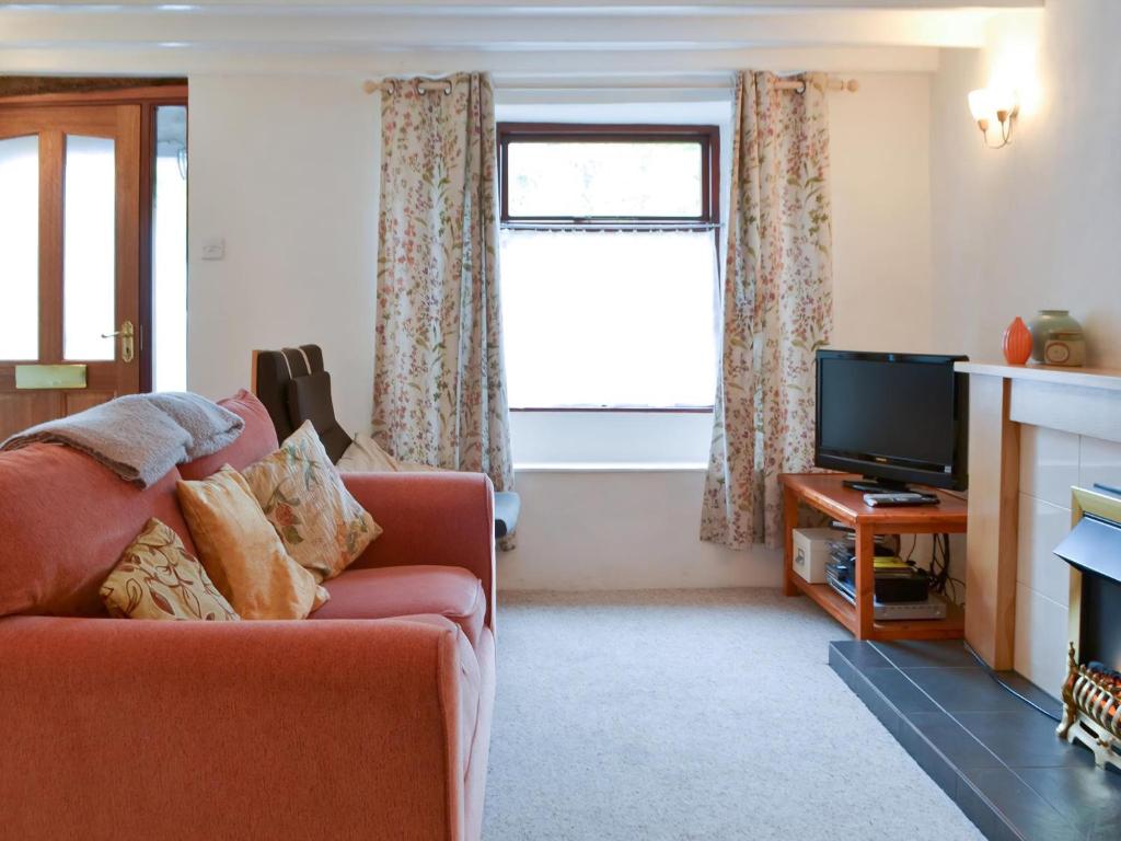 un salon avec un canapé et une télévision dans l'établissement Annie's Cottage, à Duddon