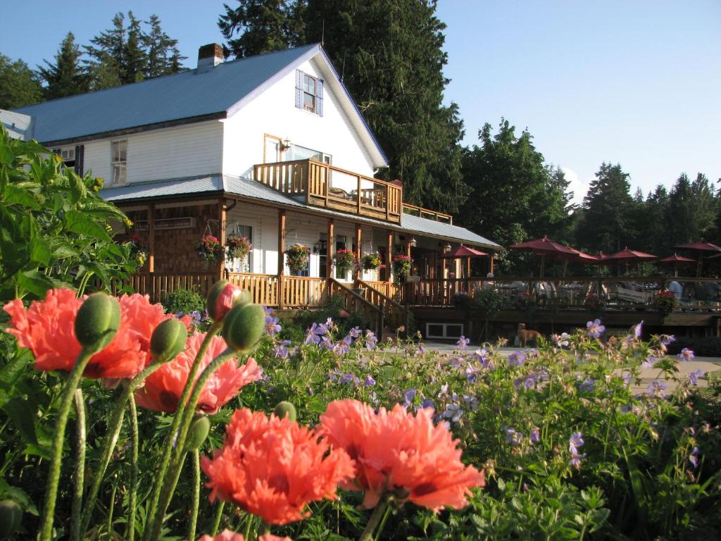 ein weißes Haus mit Blumen davor in der Unterkunft Heriot Bay Inn in Heriot Bay