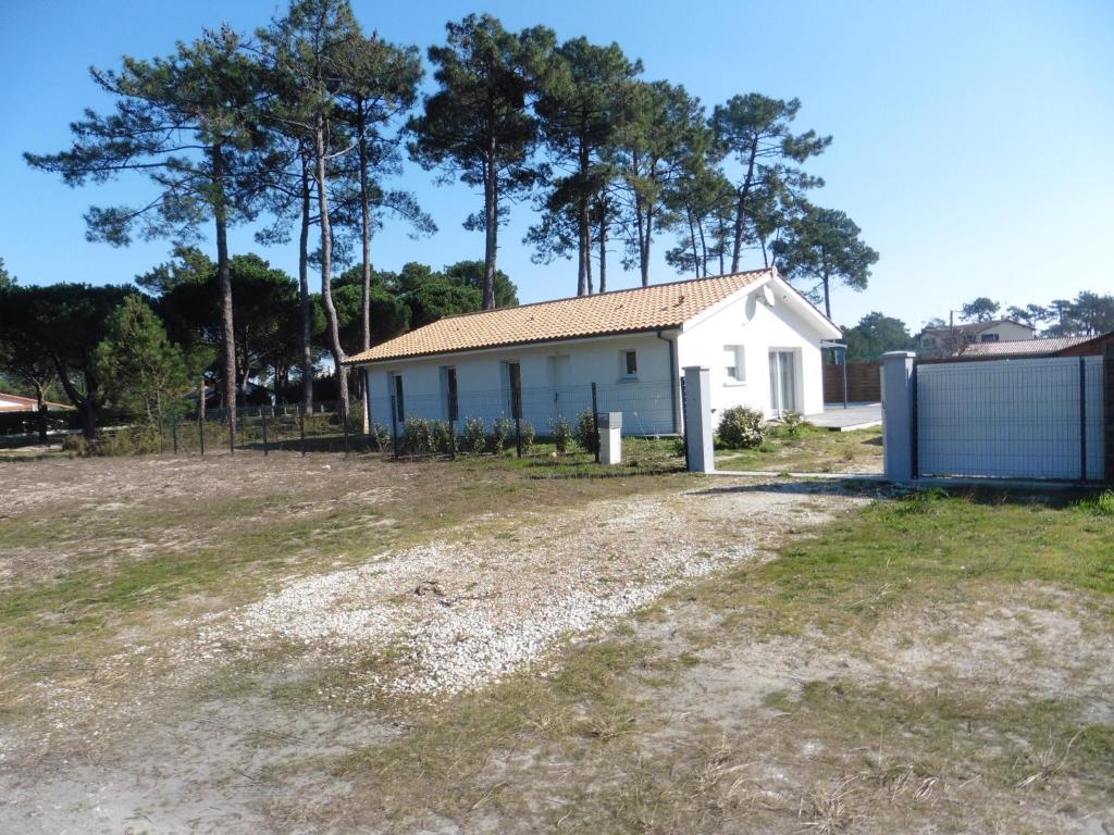 une maison blanche avec des arbres en arrière-plan dans l'établissement bee free, à Montalivet-les-Bains
