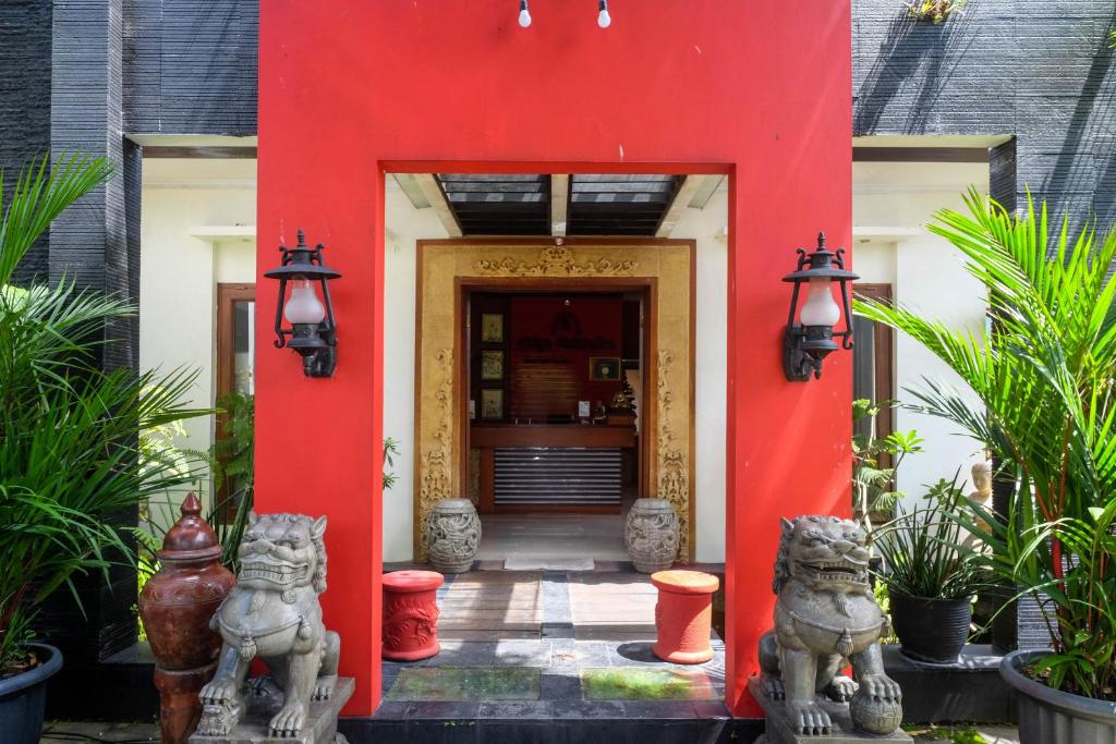 ein rotes Gebäude mit zwei Statuen vor einer Tür in der Unterkunft Urbanview Omah Eka Santi by RedDoorz in Yogyakarta