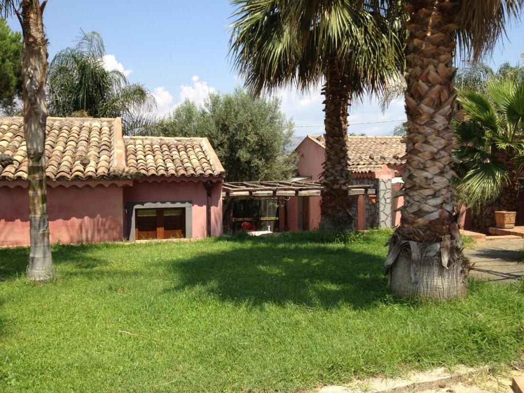 una casa rosa con palmeras en el patio en Villa del Nespolo, en Fiumefreddo di Sicilia