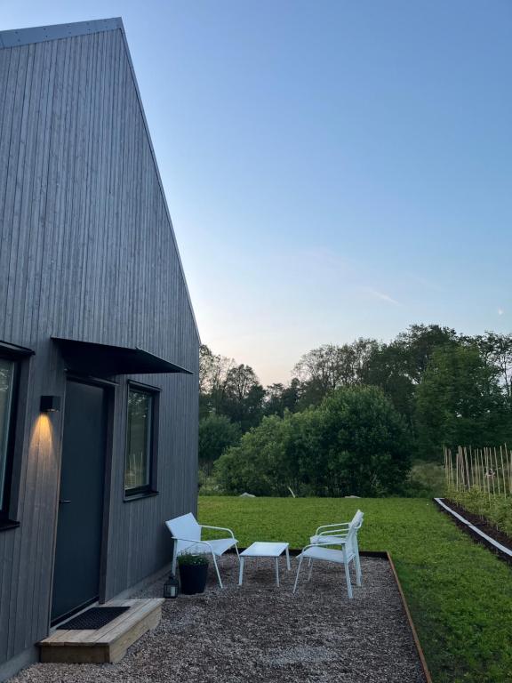 a patio with two white chairs and a building at Nybyggd gästlägenhet med sovloft in Falkenberg