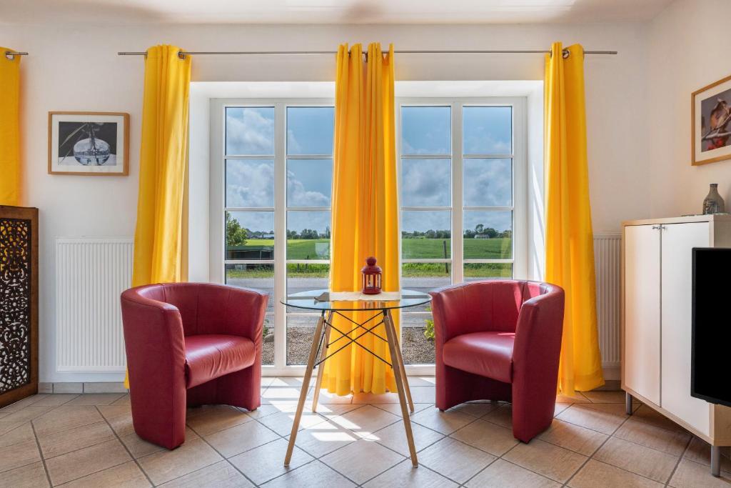 ein Wohnzimmer mit orangefarbenen Vorhängen und einem Tisch und zwei Stühlen in der Unterkunft Bi Pasders in Nordstrand