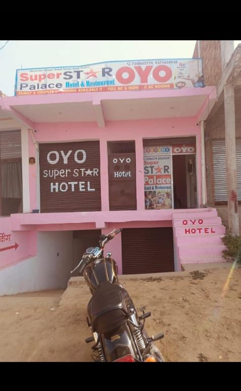 a motorcycle parked in front of a pink building at Super Star hotel in Derāpur