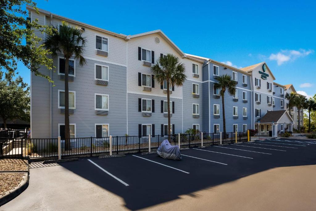 un gran edificio de apartamentos con un aparcamiento con palmeras en WoodSpring Suites Orlando West - Clermont, en Clermont