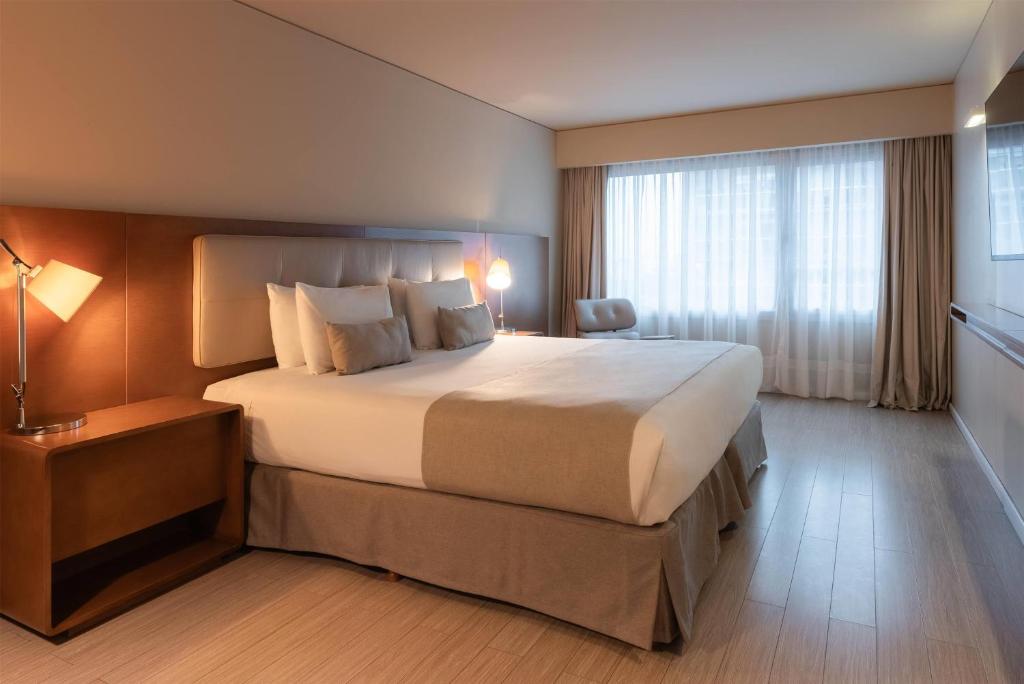 a bedroom with a large bed and a large window at Dazzler by Wyndham Montevideo in Montevideo