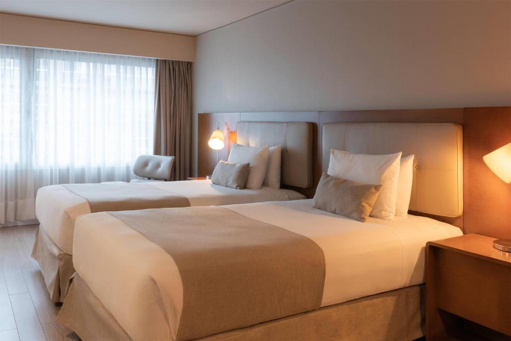 a hotel room with two beds and a chair at Dazzler by Wyndham Montevideo in Montevideo
