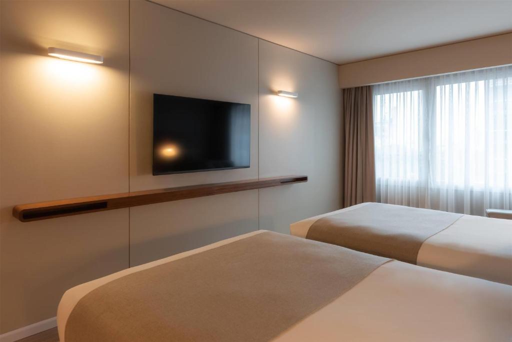a hotel room with two beds and a flat screen tv at Dazzler by Wyndham Montevideo in Montevideo
