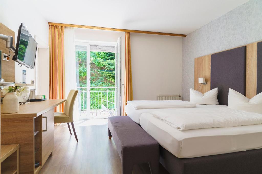 a hotel room with two beds and a desk at Stadthotel Pfeffermühle in Gengenbach