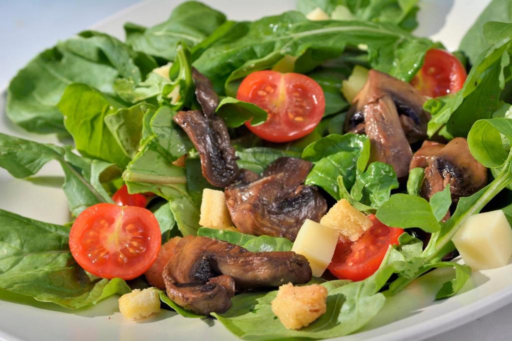 a salad with meat and tomatoes on a white plate at Gastronomy Hotel Kritsa in Portaria