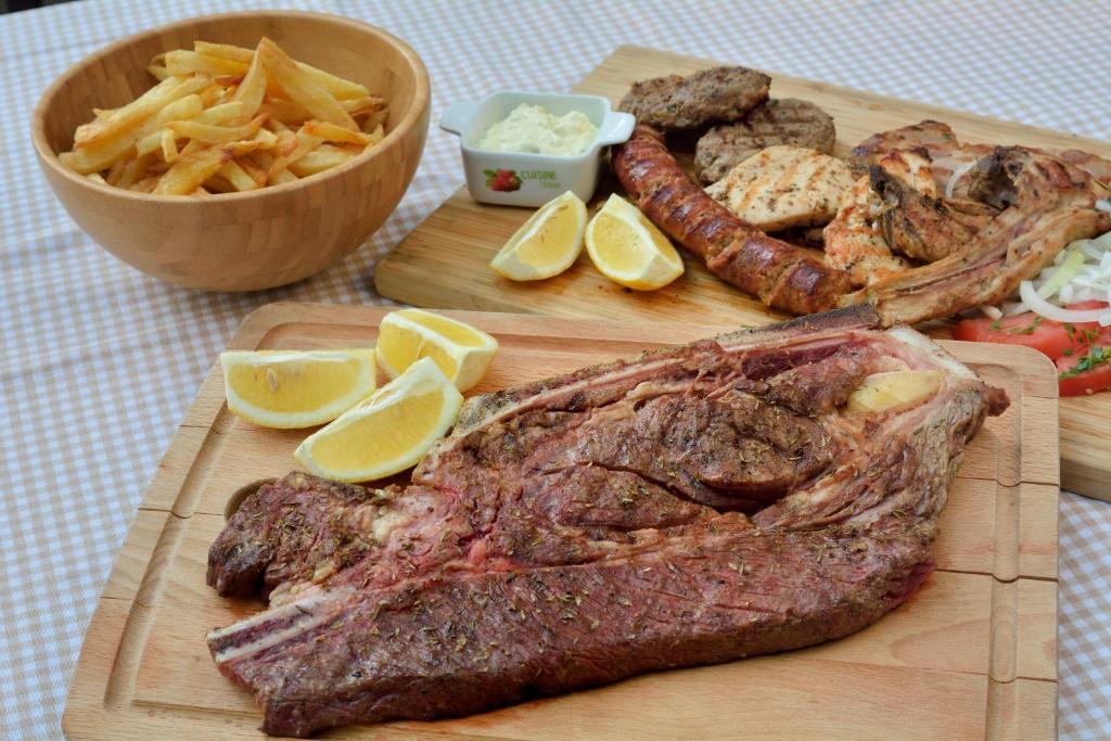 a wooden cutting board with a steak and french fries at Gastronomy Hotel Kritsa in Portaria
