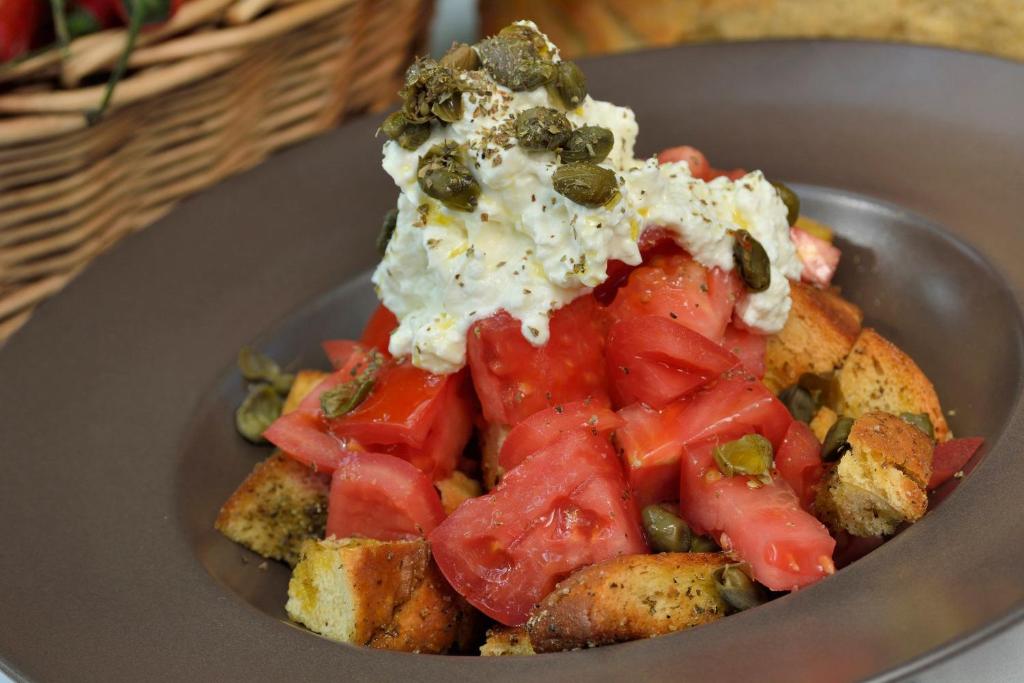 a bowl of food with tomatoes and other vegetables at Gastronomy Hotel Kritsa in Portaria