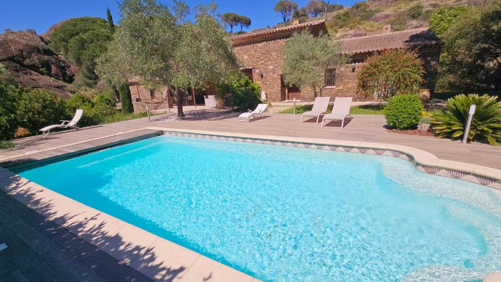 une piscine avec des chaises et une maison dans l'établissement Villa La Maurette Provenzalische Steinhaus - mitten in der Natur mit privatem Pool und Garten by Riviera HomeLife, à Roquebrune-sur Argens