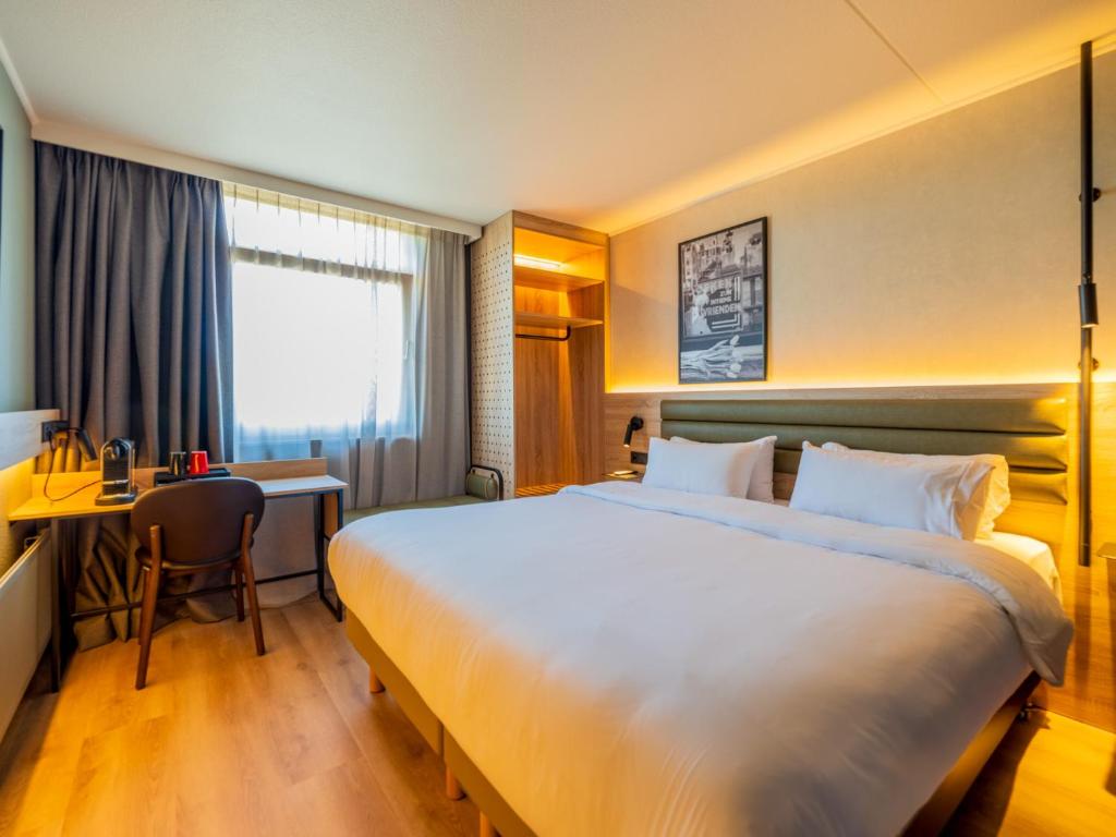Una habitación de hotel con una cama grande y un escritorio. en Campanile Hotel &amp; Restaurant Zwolle, en Zwolle