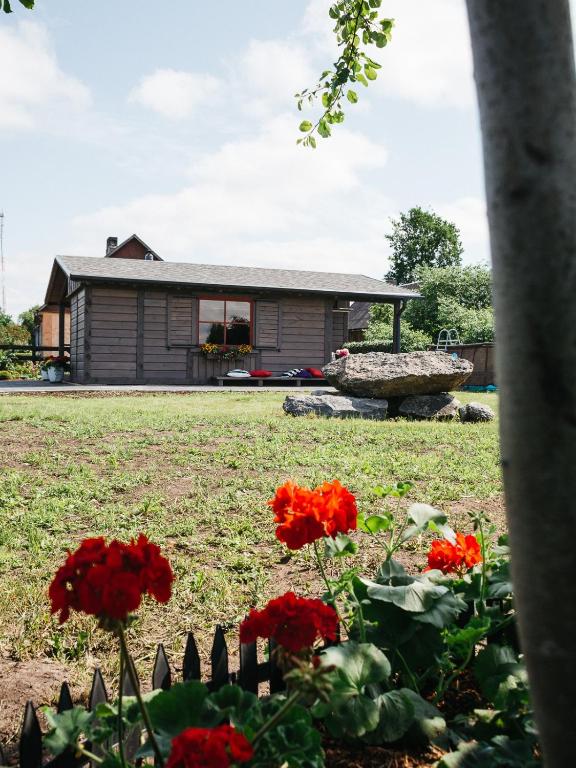 a house with red flowers in front of it at Goldingen Stone Retreat - Hot Tub and Nature in Kuldīga