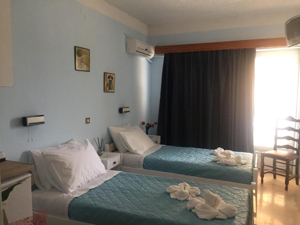 a hotel room with two beds and a window at Tzakis Studios Lassi in Argostoli