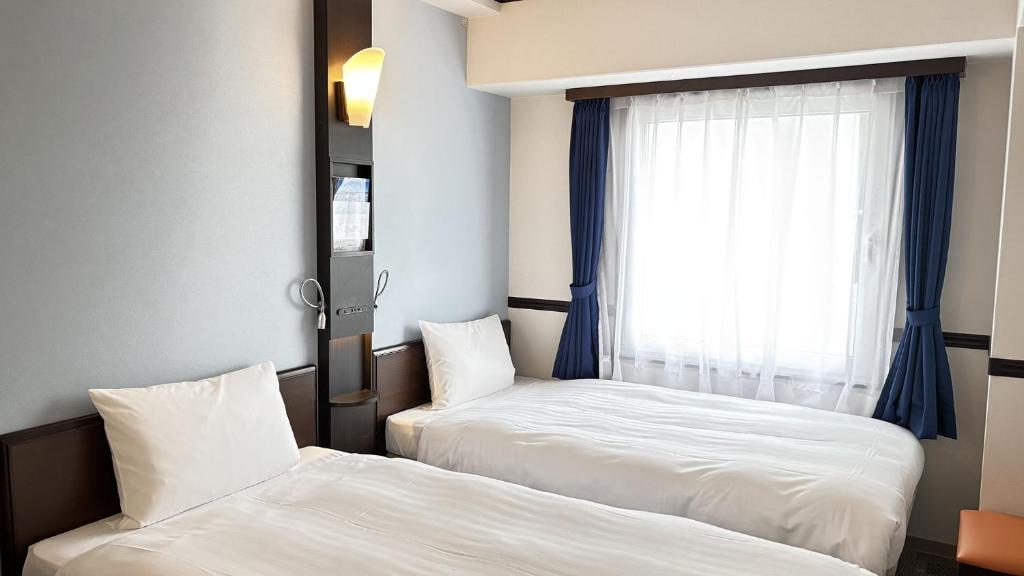Кровать или кровати в номере Toyoko Inn Tokyo Seibu Ikebukuro sen Higashi kurume eki Nishi guchi