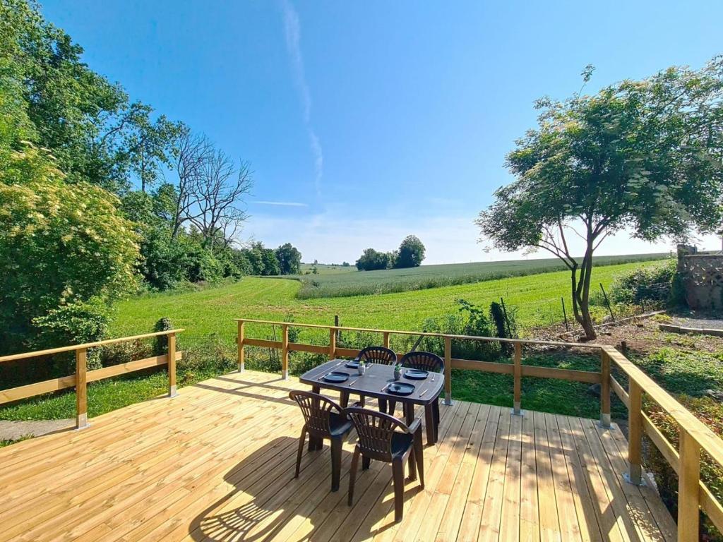 a patio with a table and chairs on a wooden deck at Le Chalet NaturZen Terrasse Panoramique & Nature près de Dinant in Hastière-par-delà