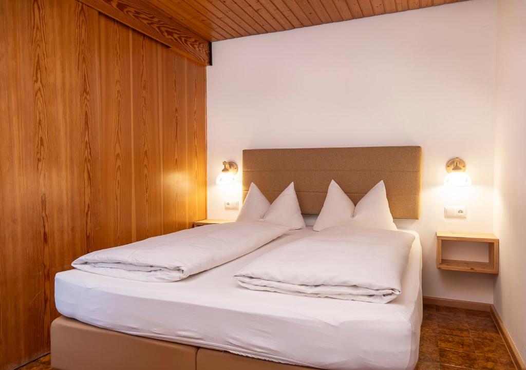 a bedroom with a bed with white sheets and pillows at Gästehaus Etschmann in Riezlern