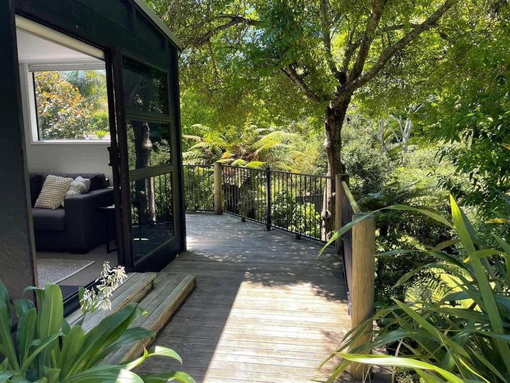 a wooden pathway leading to a patio with a tree at Huatoki Hideaway Peaceful Central Location in New Plymouth