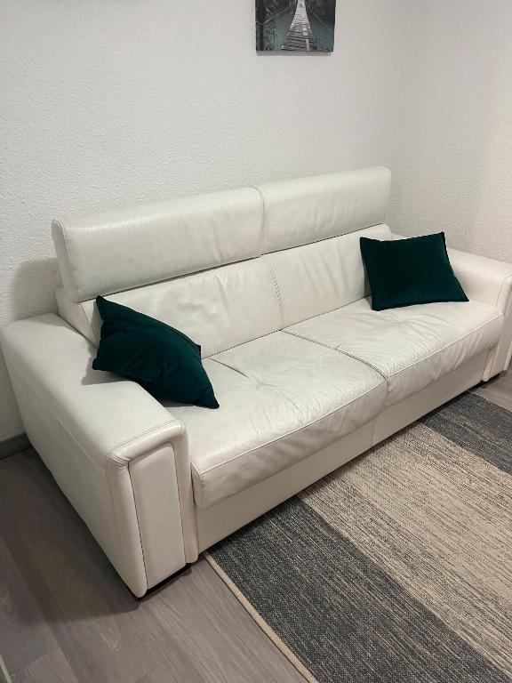 - un canapé blanc avec 2 oreillers verts dans l'établissement Studio En Station, à Arâches-la-Frasse