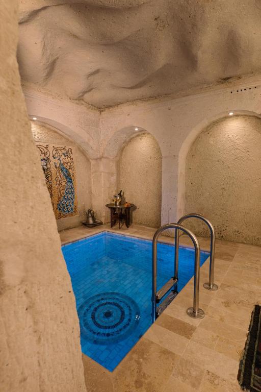 a swimming pool in a stone building with a blue swimming pool at Cappadocia Cave Suites Adult Only in Goreme