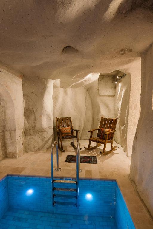 a room with two chairs and a swimming pool at Cappadocia Cave Suites Adult Only in Goreme