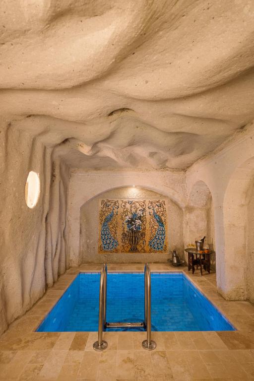 a swimming pool in a cave with a stone wall at Cappadocia Cave Suites Adult Only in Goreme