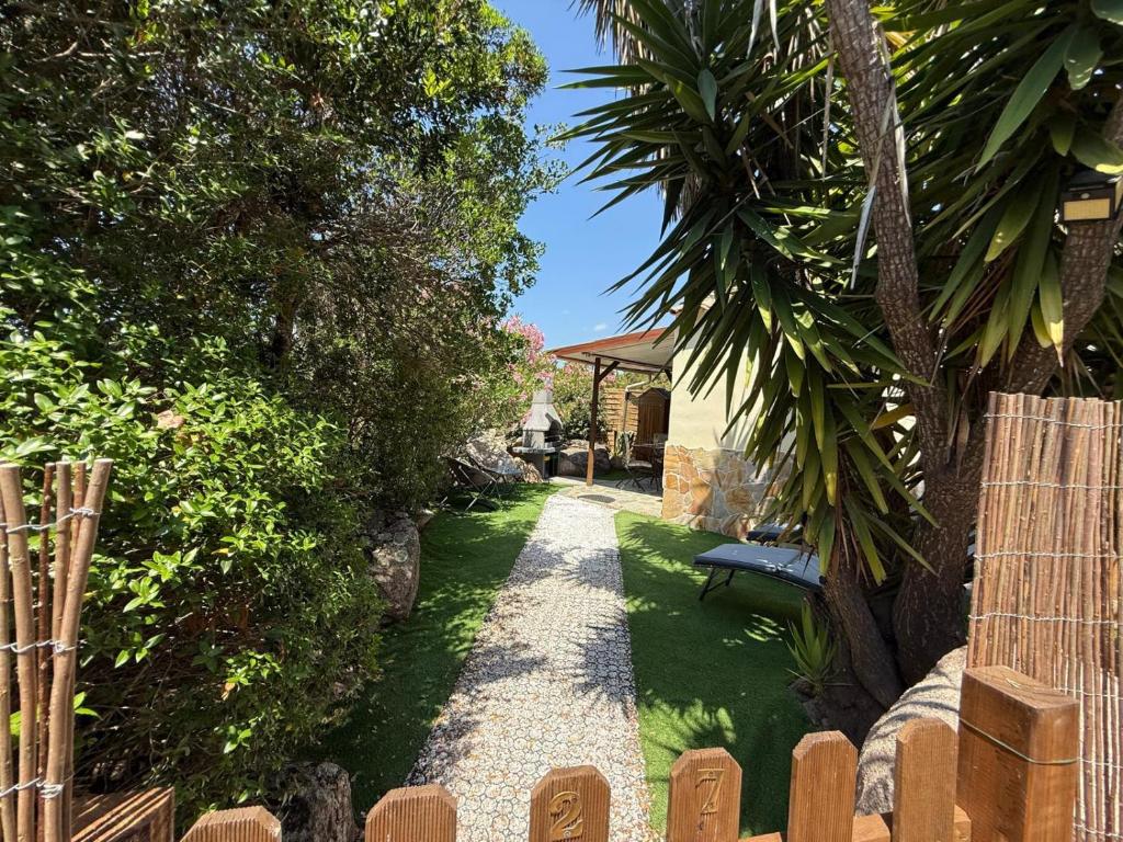 un jardin avec un chemin de gravier et un banc dans l'établissement Studio de charme à 300 m de la Plage de Santa Giulia, à Porto-Vecchio