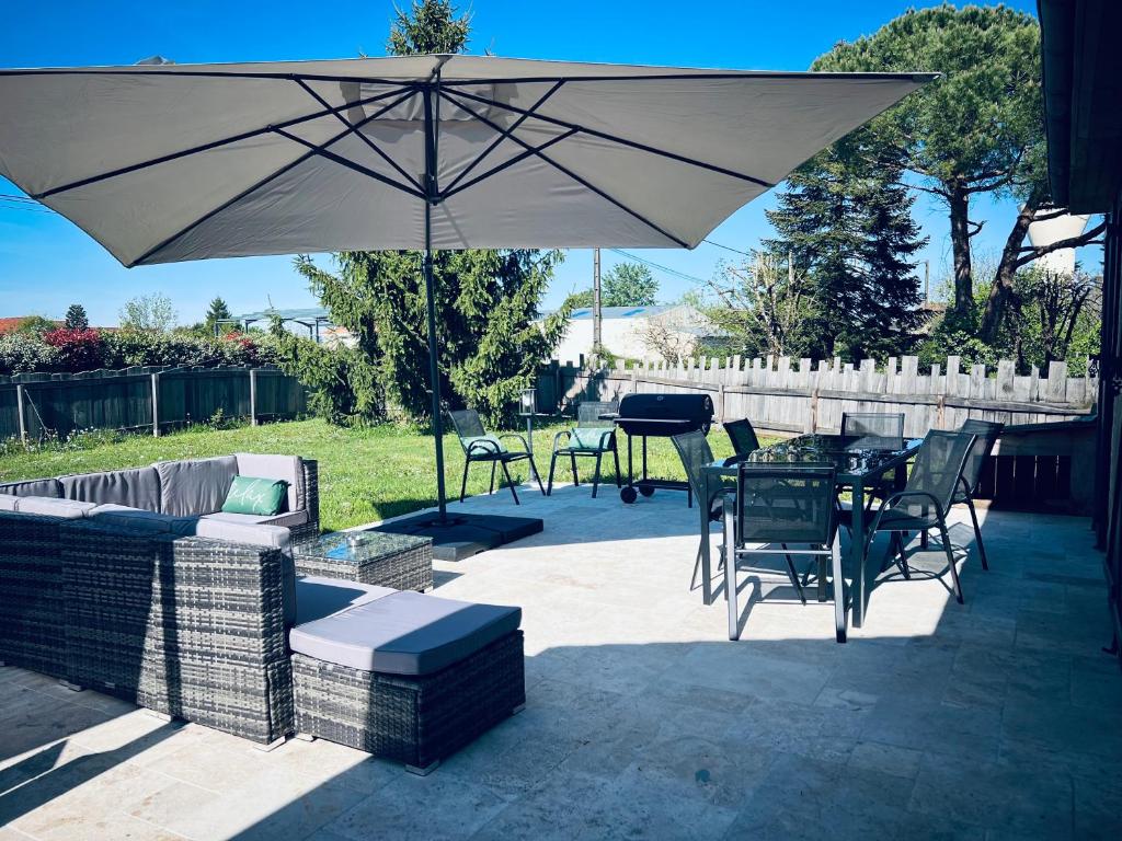 un patio avec une table, des chaises et un parasol dans l'établissement Maison Salignac 9 personnes, à Salignac Eyvigues
