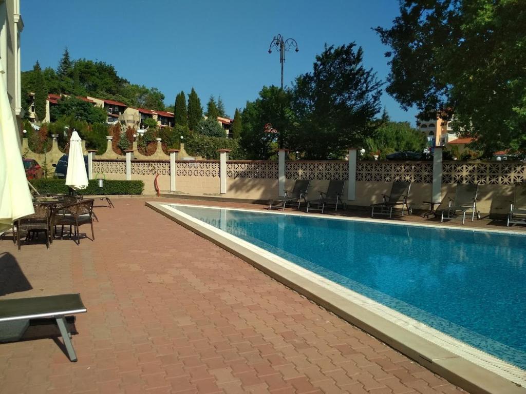 a swimming pool with chairs and umbrellas next to a fence at Квартира студия Villa Astoria 2 Болгария Солнечный берег in Elenite