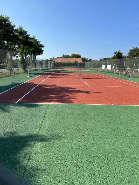 a tennis court with a net on top of it at Appartement cosy avec piscine chauffée ouverte du 15-06 au 15-09 in Cabourg