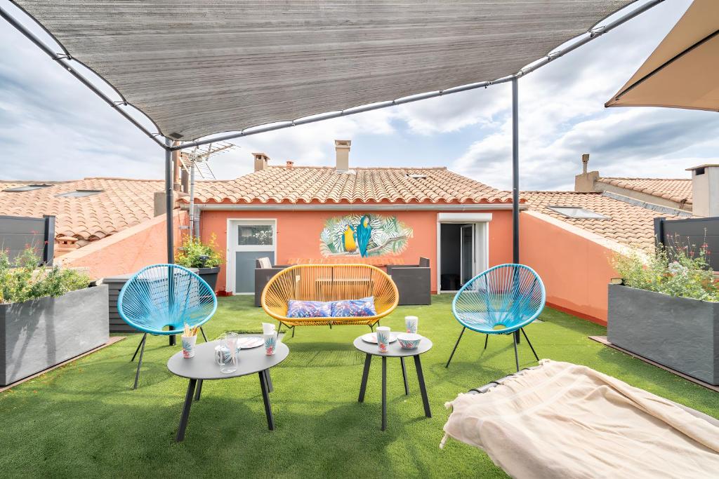 a patio with three chairs and a table on the grass at Le Parcours Cathare in Olonzac