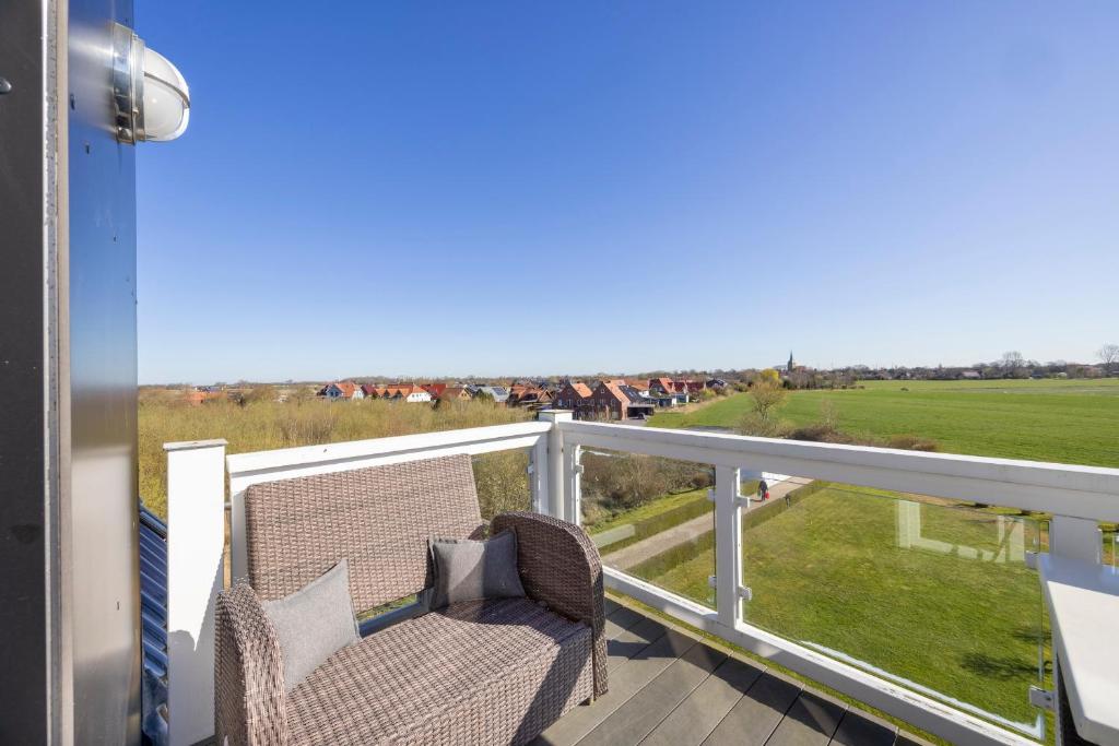 a balcony with a chair and a view of a field at Resort Deichgraf Resort Deichgraf 27-21 in Wremen