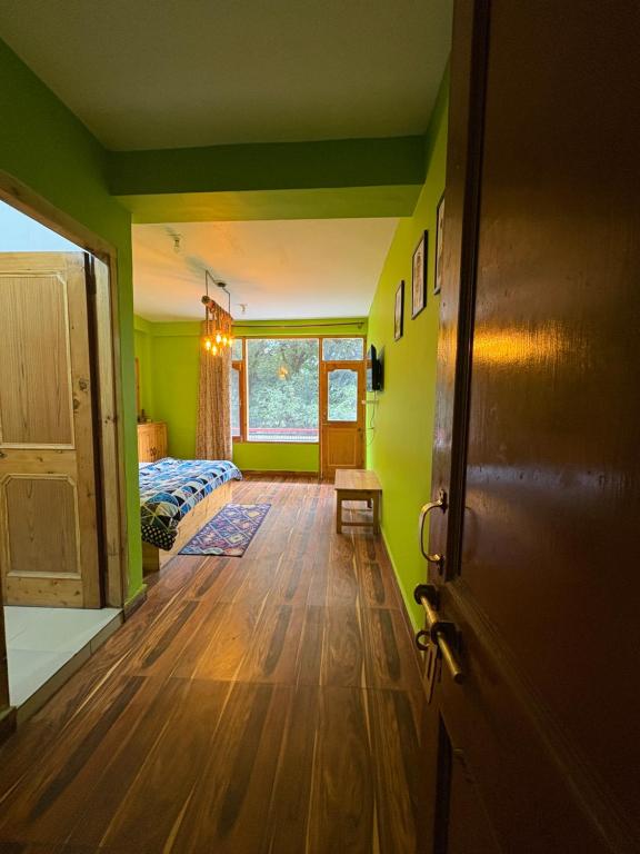 Zimmer mit grünen Wänden, einem Bett und einer Tür in der Unterkunft Jack of all in Manali