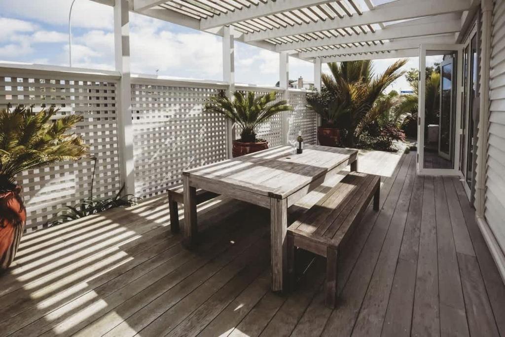 Una terraza de madera con una mesa de madera y un banco. en The Front Office - charming 3BR heritage home, en New Plymouth